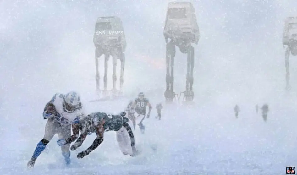 A group of dogs in the snow with two at-ats.